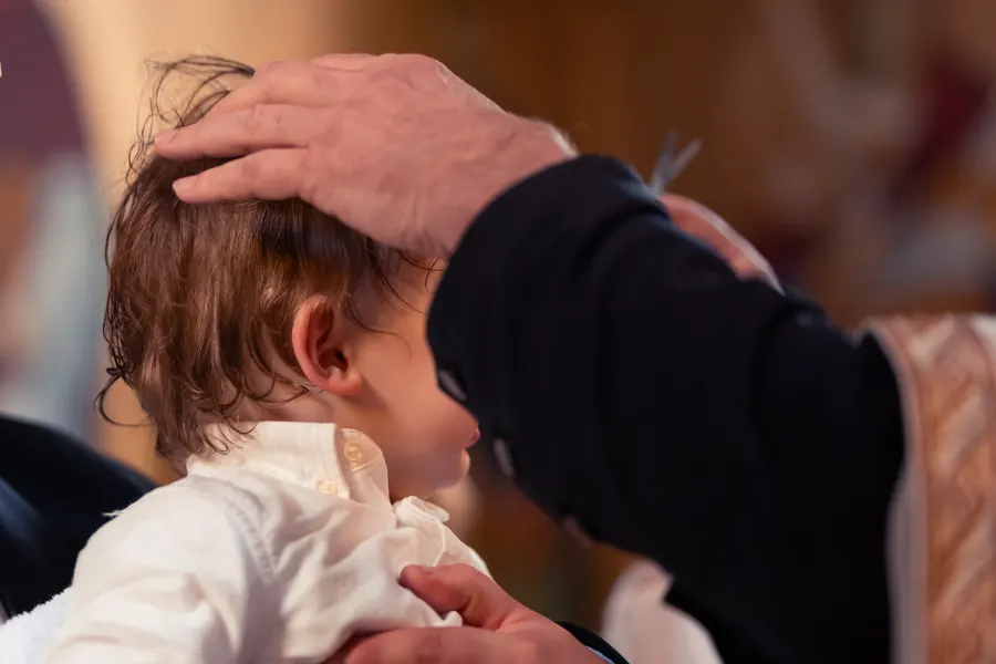 A family gathered closely for a christening blessing