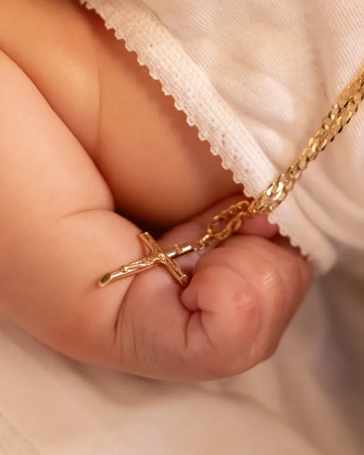 Baby hand holding cross detail during an Orthodox christening in Melbourne