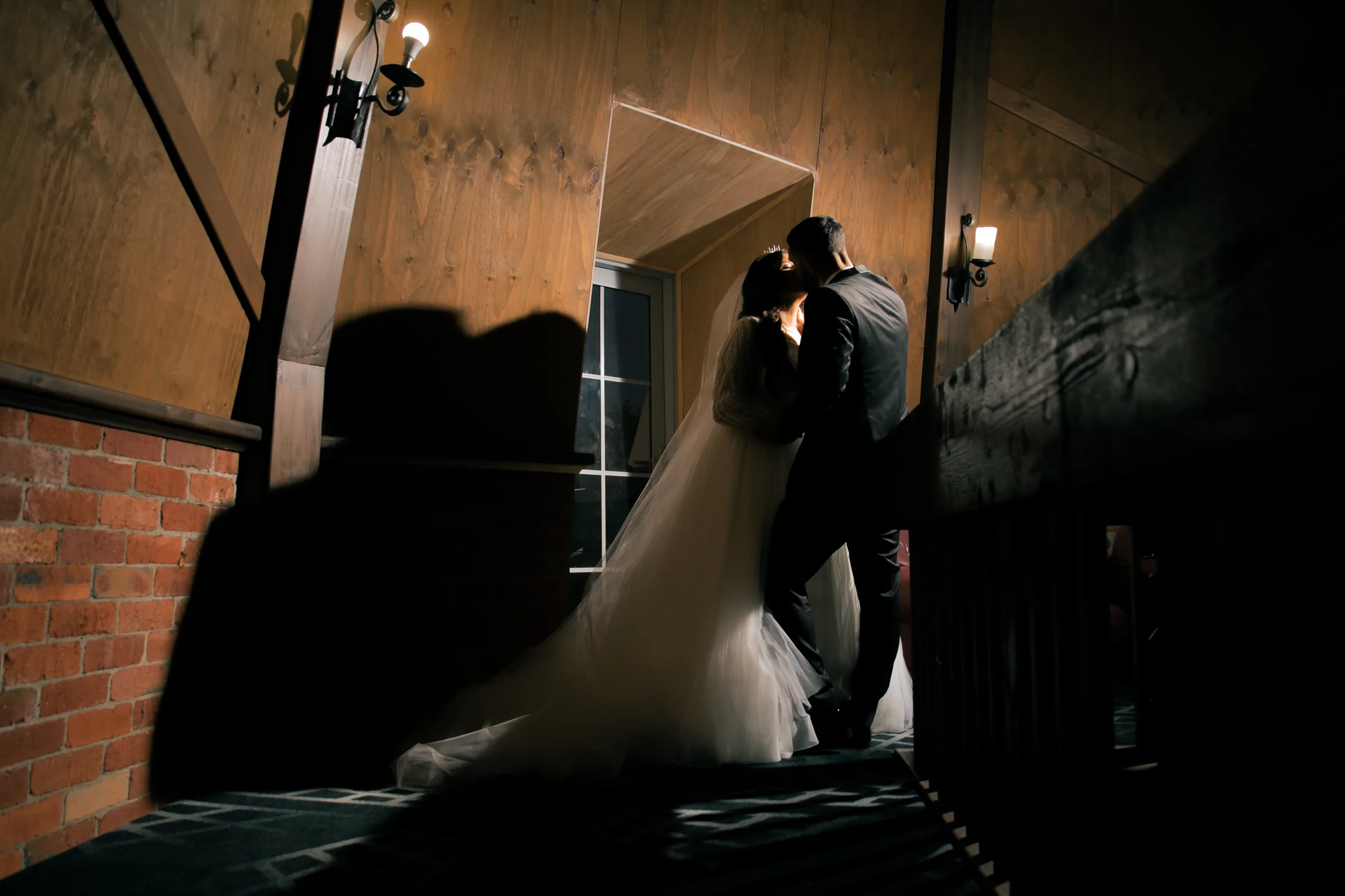 Bride and groom share a quiet kiss in warm doorway light, photographed by Royale Photography in Melbourne.